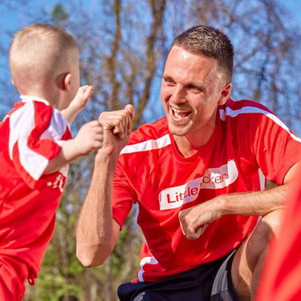 Coach high fiving small child outdoors 