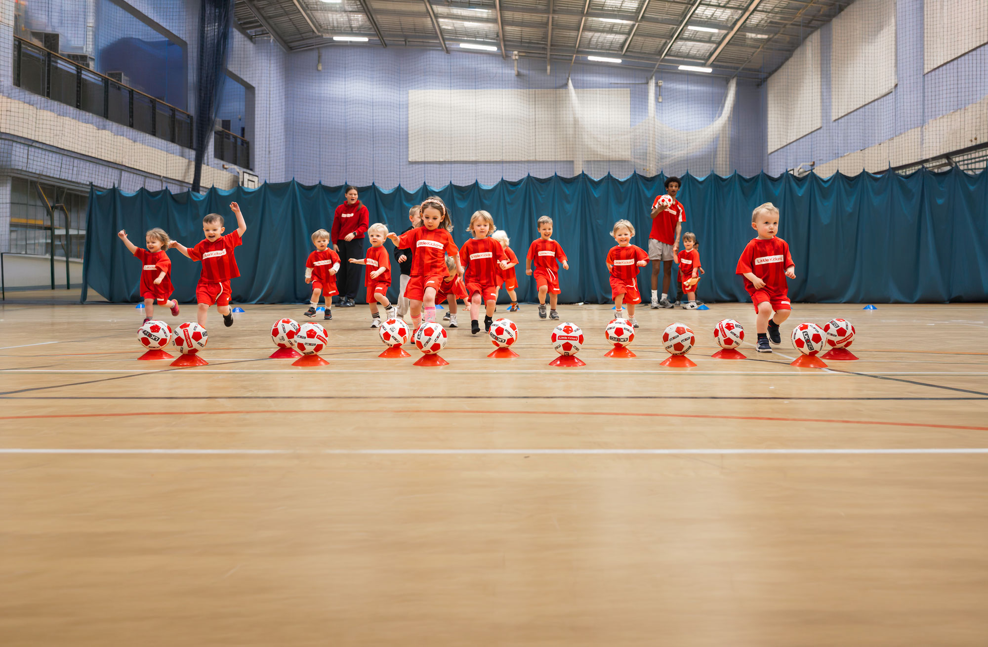 Little Kickers players running to kick footballs